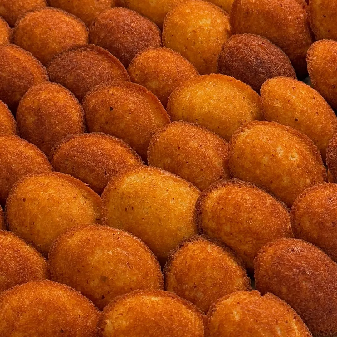 Golden potato croquettes lined up by the dozen
