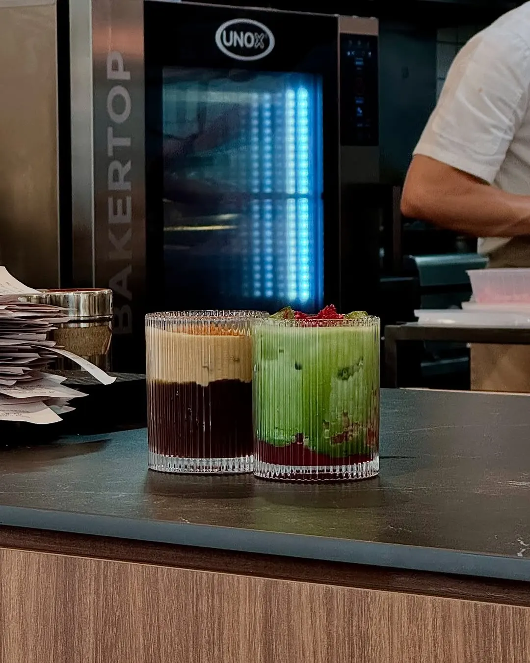 Two ribbed glasses of cold drinks resting on the counter