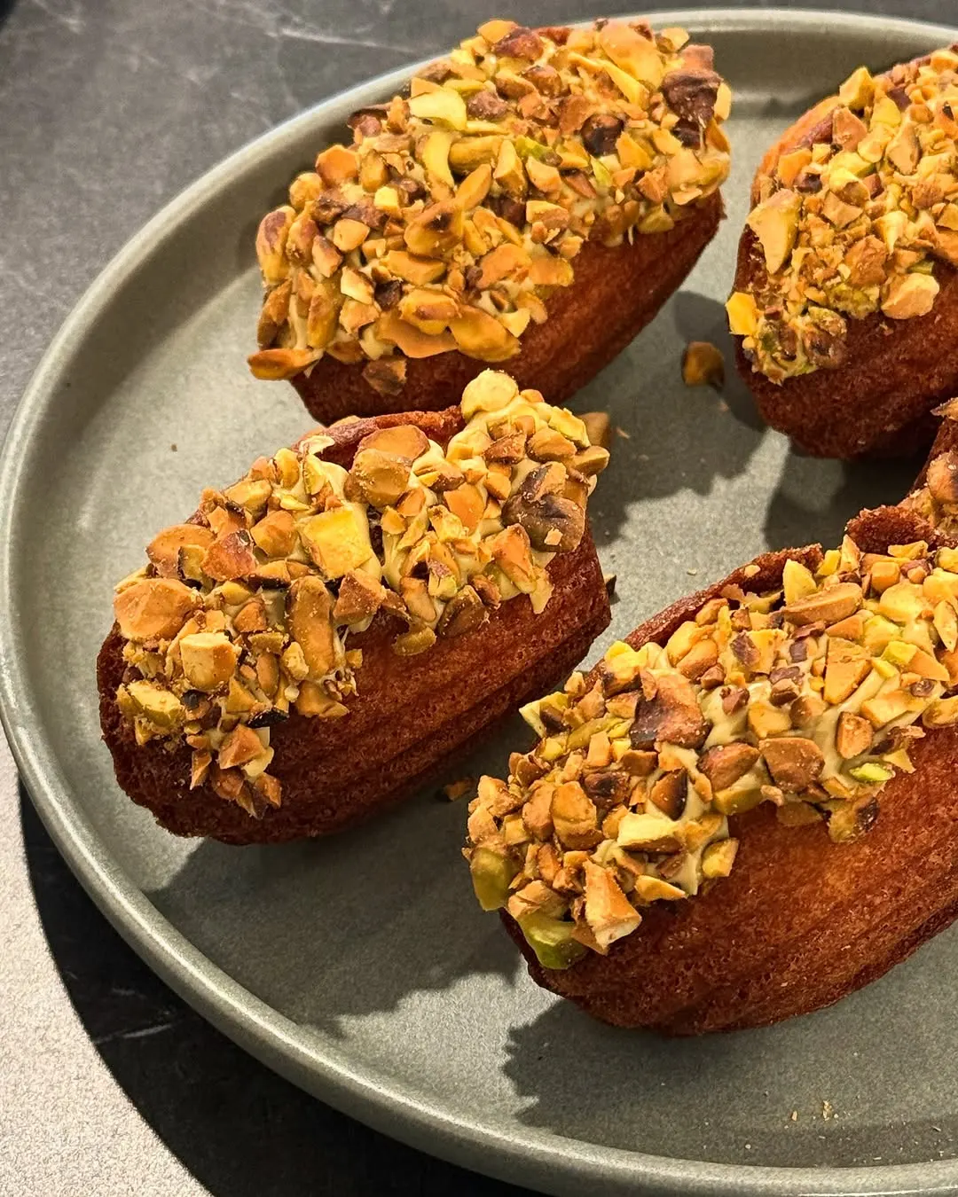 Pistachio-dipped madeleines on a stone plate