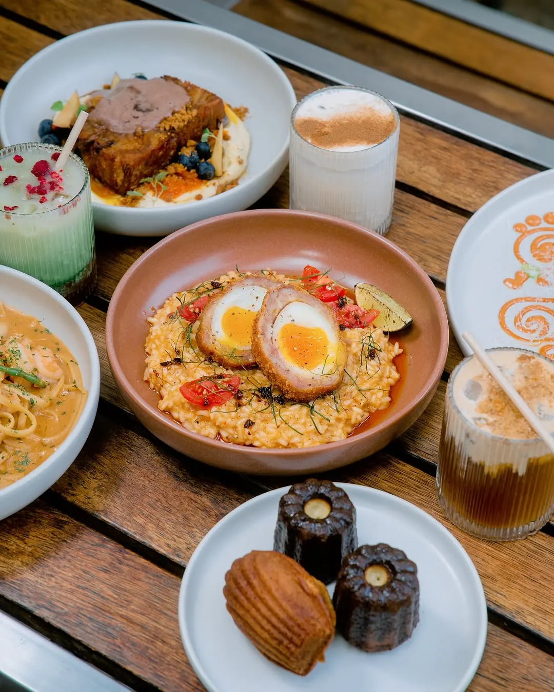 Soft-yolk scotch egg over tomato risotto, set on a shared brunch table